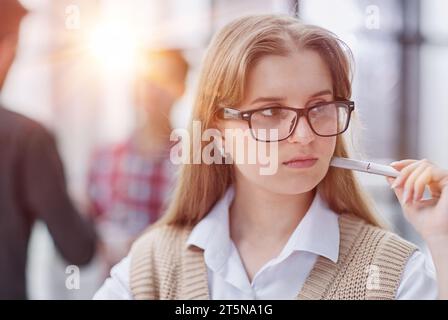 Ein ernstes Mädchen hält einen Stift in den Händen und denkt über etwas nach Stockfoto