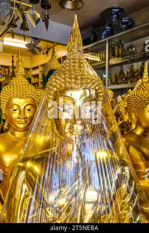 Eine Gruppe großer, goldener Buddhas zum Verkauf. An einer religiösen Ikone, einem Reliquienladen entlang der Bamrung Mueang Road in Bangkok, Thailand. Stockfoto