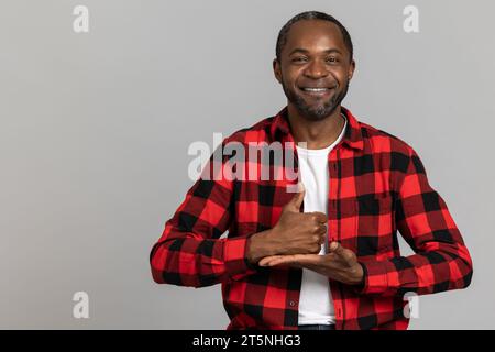 Fröhlicher, schwarz bärtiger Mann, der ein rotes kariertes Hemd trägt und taubstumme Gesten zeigt Stockfoto