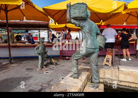 Statuen eines Fischers, eines Jungen und einer kleinen Katze im Hafen von Marsaxlokk und der Kirche unserer Lieben Frau. Malta Stockfoto