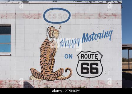 Seite des alten Esso-Bahnhofs, jetzt leer, an der Route 66, ein Cartoon-Tiger auf der Seite gemalt und sein Slogan Happy Motoriing, Tucumcari, New Mexico, USA. Stockfoto