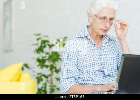 Porträt einer älteren Frau, die Laptop aussieht Stockfoto