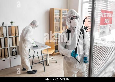 Personen, die Schutzausrüstung tragen, um gefährlichen Bereich zu desinfizieren 2 Stockfoto