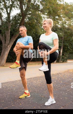 Ältere Ehepaare mit Seitenansicht, die sich vor dem Training im Freien aufwärmen Stockfoto