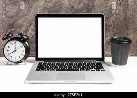 Wecker, Einweg-Kaffeetasse mit offenem weißem Laptop-Schreibtisch Stockfoto