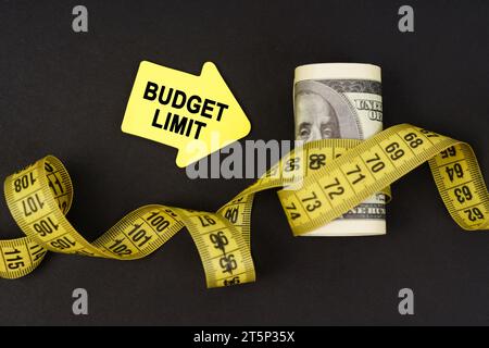 Geschäftskonzept. Auf einer schwarzen Oberfläche befinden sich in Maßband gewickelte Dollars und Aufkleber mit der Aufschrift "Budget Limit" Stockfoto