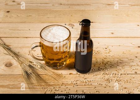 Schließen Sie Bierglasflasche mit Ohren Weizen Holz Hintergrund Stockfoto