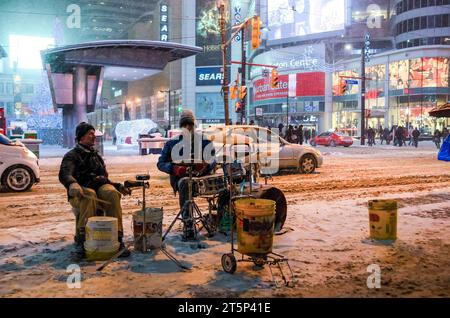 Toronto, Kanada - 14. Dezember 2013: Straßenmusiker spielen auf dem Yonge-Dundas Square während eines Schneesturms in der Nacht Stockfoto