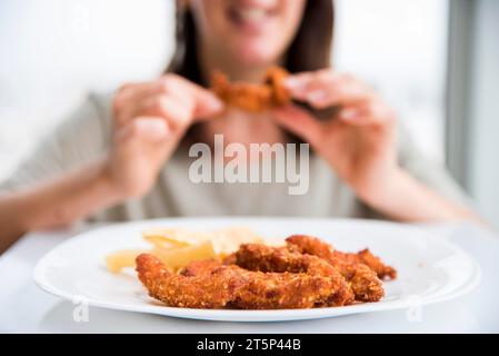 Gebratenes Huhn in der Nähe einer essenden Frau Stockfoto
