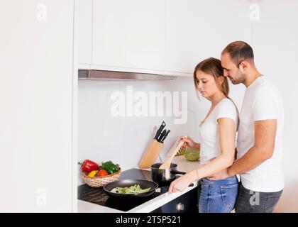 Mann, der seine Frau liebt, Essen zu kochen, neuer Elektroherd mit Induktionskochküche Stockfoto