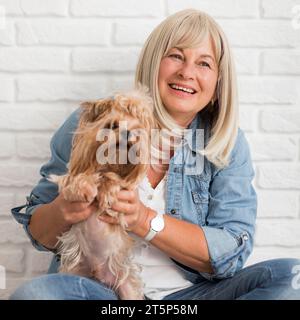 Mittelgroße glückliche Frau, die Hund hält Stockfoto