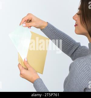 Frau, die einen Umschlag mit leerem Papier hält Stockfoto