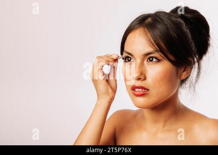 Frau, die ihre Augenbrauen mit einer Pinzette benutzt Stockfoto