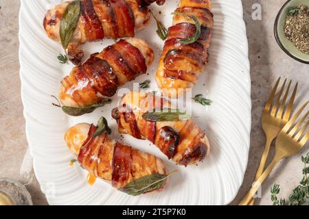 Weihnachtsschweine in Decken, Würstchen in Speck mit Salbeiblättern Stockfoto