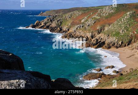Sanft abfallende Klippen zum hellblauen Meer mit sandigem Porth Chapel Beach in der Nähe des Minack Theaters in West Penwith, Cornwall von der Südwestküste Stockfoto