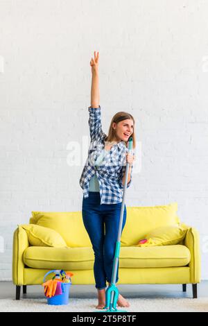 Glückliche Frau, die mit Mopp nach Hause tanzt Stockfoto