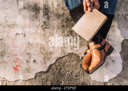 Sitzende Person Hände mit geschlossenem Buch Stockfoto
