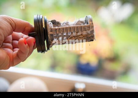 Ein verstopfter verschmutzter Filter aus der Waschmaschine wird entfernt und gereinigt, um die Verstopfung zu beheben. Stockfoto