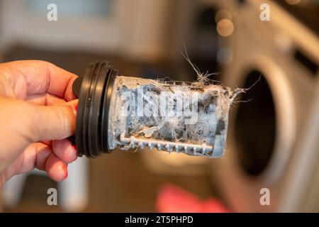 Verstopfter verschmutzter Filter in der Waschmaschine, voller Haare und Kalk, Maschine im Hintergrund Stockfoto