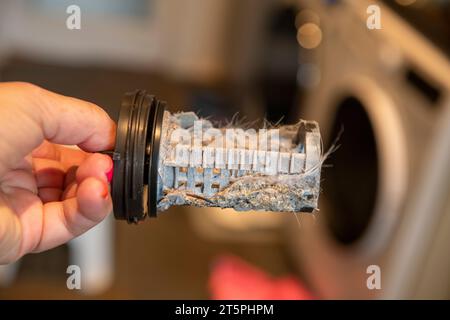 Verstopfter verschmutzter Filter in der Waschmaschine, voller Haare und Kalk, Maschine im Hintergrund Stockfoto