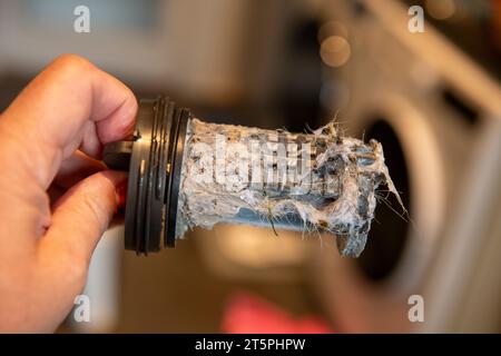 Verstopfter verschmutzter Filter in der Waschmaschine, voller Haare und Kalk, Maschine im Hintergrund Stockfoto