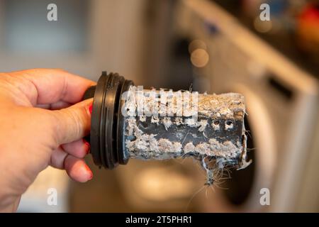 Verstopfter verschmutzter Filter in der Waschmaschine, voller Haare und Kalk, Maschine im Hintergrund Stockfoto