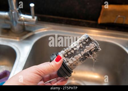 Ein verstopfter verschmutzter Filter aus der Waschmaschine wird entfernt und gereinigt, um die Verstopfung zu beheben. Stockfoto