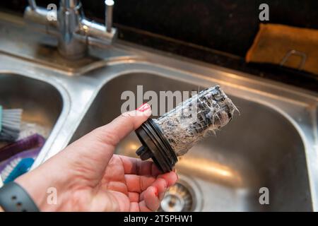 Ein verstopfter verschmutzter Filter aus der LG Waschmaschine wird entfernt und gereinigt, um die Verstopfung zu beheben. Stockfoto