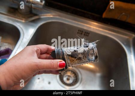 Ein verstopfter verschmutzter Filter aus der LG Waschmaschine wird entfernt und gereinigt, um die Verstopfung zu beheben. Stockfoto
