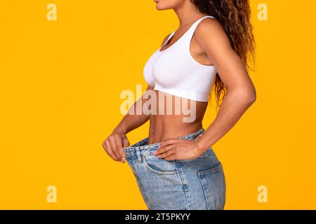 Die Nicht Erkennbare Schwarze Frau Trägt Oversize Jeans Zeigt Weight Loss, Studio Stockfoto