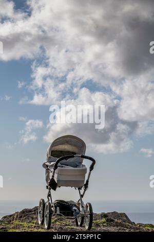 Ein leerer Kinderwagen liegt auf einem Berg mit Wolken im Hintergrund Stockfoto