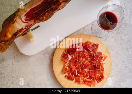 Spanische Jamón auf einem weißen Jamonera-Stand und Rotweinglas Stockfoto