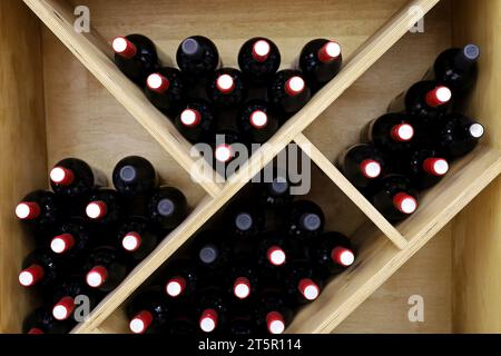 Weinflaschen in einem Holzweinregal. Spirituosengeschäft, weiß- und Rotwein Stockfoto