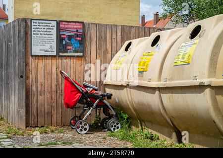 Ein Kinderwagen wurde vor einem Recyclingbehälter in der Altstadt von Memmingen, Schwaben, Bayern, gelassen. Stockfoto