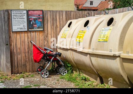 Ein Kinderwagen wurde vor einem Recyclingbehälter in der Altstadt von Memmingen, Schwaben, Bayern, gelassen. Stockfoto