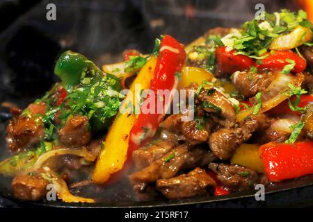 mexikanisches Essen, das Hühnchen und Rindfleisch auf heißem Brateller raucht Stockfoto