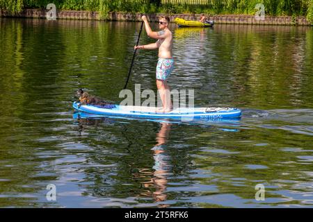 14. Juni 2023 Ein junger Rüde und sein Hund auf einem Paddelbrett auf der Themse im Cookham Village in Berkshire England an einem heißen Sommernachmittag Stockfoto