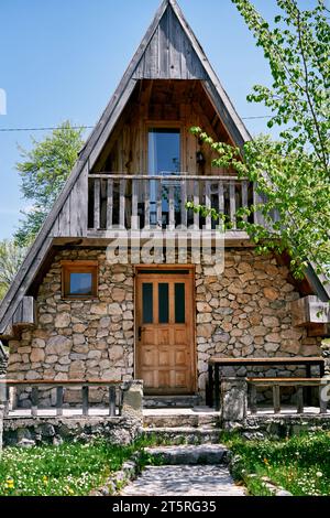 Gepflasterter Weg zu einem dreieckigen Steinhaus in einem grünen Garten Stockfoto