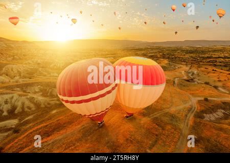 Kappadokien-Ballons steigen in den Himmel. Während sie die ersten Sonnenstrahlen einfangen, strahlen diese bunten Ballons mystische Ausstrahlung auf einzigartige Gipfel unter ihnen aus Stockfoto