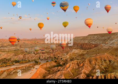 In Kappadokien steigen Ballons in den Himmel. Strahlende Ballons ergreifen das schwindende Sonnenlicht und projizieren eine mystische Ausstrahlung auf die surrealen Gipfel Stockfoto