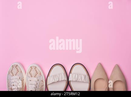 Verschiedene beige Sommerschuhe für Damen auf pastellrosa Hintergrund mit Kopierraum oben und in der Mitte. Stylische Sneakers, Sandalen und Pumps. Flache Lage, bis Stockfoto