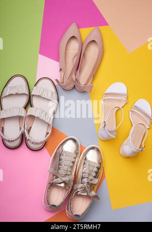 Verschiedene Sommerschuhe für Damen auf mehrfarbigem Hintergrund: Sandalen, lässige Sneaker, spitz zulaufende Flats. Draufsicht, flach. Fashion Blog oder Magazin Stockfoto