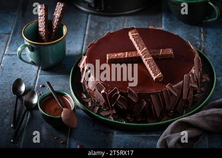 Köstlicher Schokoladenkuchen aus Milch, Nüssen und Glasur. Schokoladenkuchen auf dunkelblauem Tisch. Stockfoto