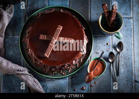 Süßer Schokoladenkuchen mit dunklen Schokoladentafeln. Schokoladenkuchen auf dunkelblauem Tisch. Stockfoto