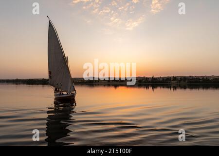 Felucca traditionelles ägyptisches Segelboot fährt bei Sonnenuntergang auf dem Nil den Fluss hinunter Stockfoto