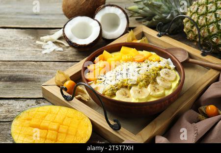 Leckere Smoothie-Schüssel mit frischem Obst, serviert auf Holztisch Stockfoto