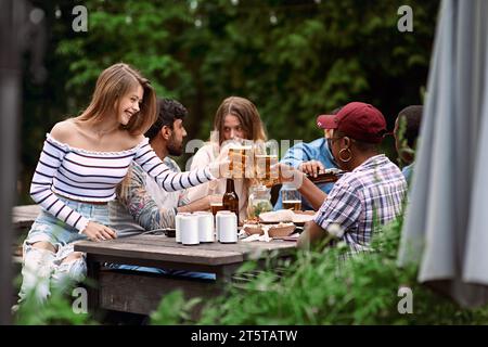 Klirrende Biergläser. Eine Gruppe von Freunden feiert draußen einen Urlaub. Festliches Treffen im Freien. Geburtstagsfeier. Leute hängen ab, dri Stockfoto