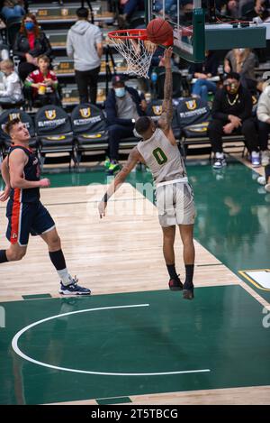 College-Basketballspieler, der während der NCAA-Action einen Layup am Rand beendet, werden mit scharfen Details und dynamischen Bewegungen auf dem Hallenplatz erfasst. Stockfoto
