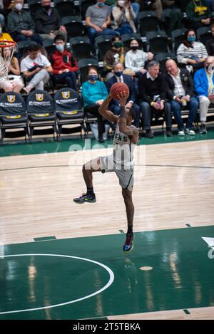 College-Basketballspieler fahren zum Rand für einen Layup während der NCAA-Action, aufgenommen mit scharfen Details und dynamischer Energie in der Halle. Stockfoto