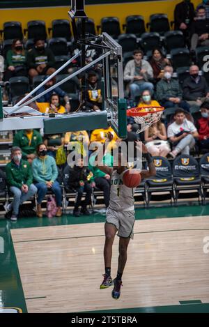 College-Basketballspieler fahren zum Rand für einen Layup während der NCAA-Action, aufgenommen mit scharfen Details und dynamischer Energie in der Halle. Stockfoto